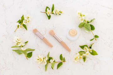 Body care products and branches of jasmine on the white background.