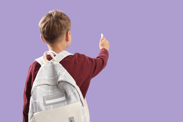 Little schoolboy with backpack and chalk piece on lilac background, back view