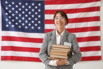 Female Asian teacher with books against USA flag. Labour Day celebration
