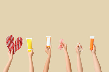 Female hands with beach accessories and flip-flops on beige background
