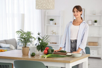 Young woman with fresh vegetables on table in dining room