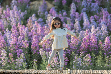 The children girl of vast flower field in full bloom stretches.
