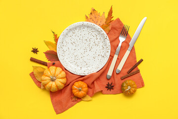 Beautiful table setting with fresh pumpkins, star anise, cinnamon and autumn leaves on yellow...