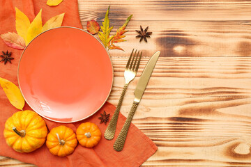 Beautiful table setting with fresh pumpkins, star anise and autumn leaves on wooden background