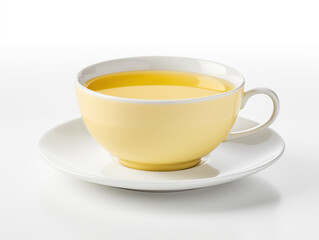 A yellow teacup filled with a yellow liquid on a white saucer on white table