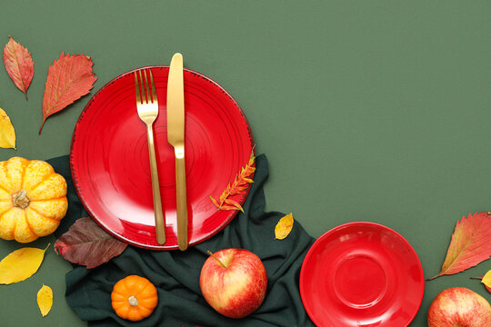 Beautiful table setting with fresh pumpkin, apples and autumn leaves on green background