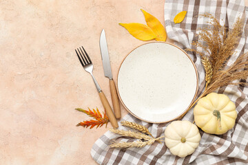 Beautiful table setting with fresh pumpkins, wheat and autumn leaves on beige background