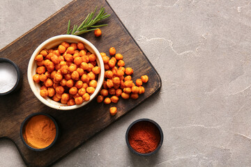 Bowl with tasty fried chickpeas, rosemary and spices on grey background