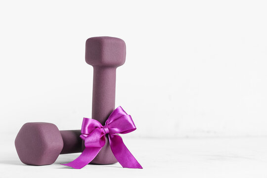Purple dumbbells with bow on white background