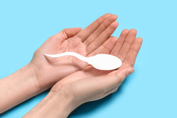 Hands with sperm cell on blue background