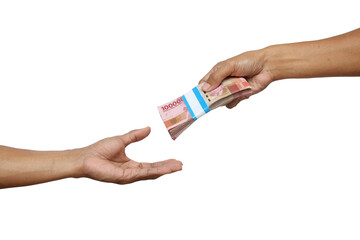 One hand offers a bundle of Indonesian Rupiah banknotes to another outstretched, open hand,...