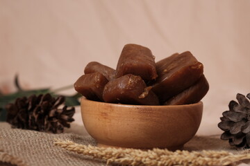 Stack of Jenang Ketan Dodol, Indonesian sweet snack made from glutinous rice flour, coconut milk, brown sugar and pandan leaves, set on rustic background