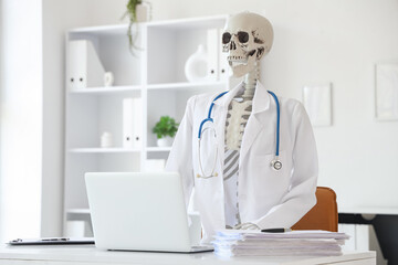 Human skeleton model with doctor's coat at desk in medical office