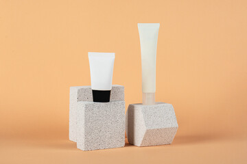 Plastic white tube for cream or lotion. Skin care or sunscreen cosmetic with stylish props on cream background.