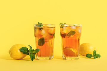 Glasses of fresh iced tea on yellow background