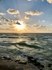 A peaceful seascape at sunset, with golden light filtering through the clouds and reflecting on...