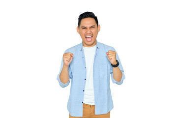 Excited young handsome Asian man in casual clothes making winner gesture with raising fist,...