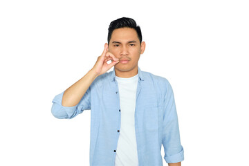 Portrait of serious young Asian man in casual clothes making zipping mouth gesture, promising to...