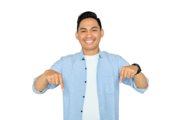 Here and now. Handsome young Asian man in casual clothes pointing finger down, looking at camera with happy expression isolated on transparent background