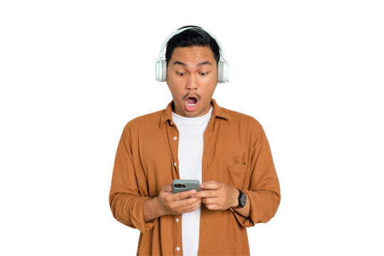 Young Asian man in casual shirt with headphones reading news on smartphone with shocked expression isolated on transparent background