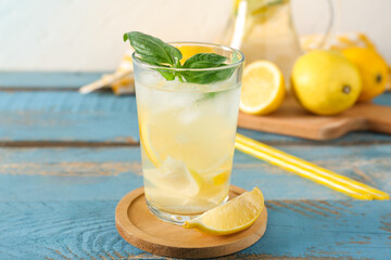 Glass of fresh lemonade with basil leaves on blue wooden table