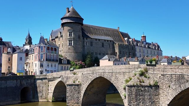 Walking view of the historic Pont Vieux aka Old Bridge with fortified medieval Laval Castle in the background, Laval, Mayenne, France.