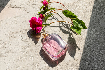 A transparent bottle of cosmetic spray or women's perfume lies on a gray cement background with...
