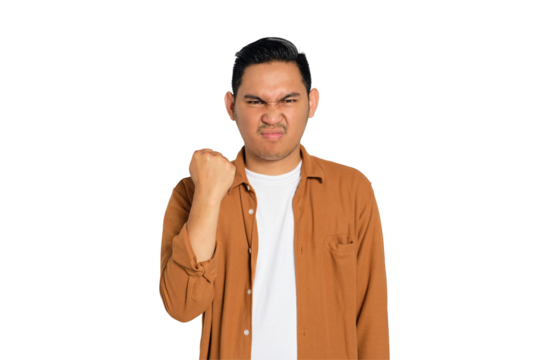 Upset young Asian man in casual shirt raising fist with angry expression isolated on transparent background