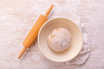Raw yeast dough with rolling pin resting and rising in a special basket