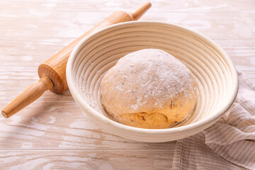 Raw yeast dough with rolling pin resting and rising in a special basket