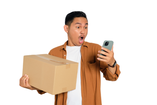 Surprised young Asian man in casual shirt holding cardboard box and using mobile phone for online shopping isolated on transparent background