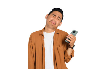 Unhappy young Asian man in casual shirt holding smartphone, receiving negative message, sad facial...
