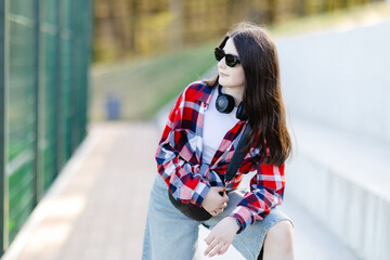 Stylish teenager posing with headphones and sunglasses in urban setting