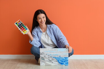 Young woman with watercolor and painting by numbers sitting near orange wall
