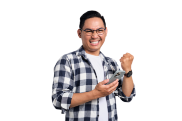 Excited young Asian man in casual shirt using smartphone for trading or chatting, making winning gesture isolated on transparent background