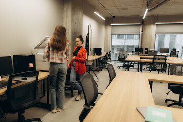 Two Women Engaged in Discussion in Modern Open-Plan Office Environment