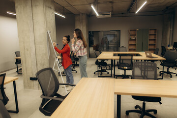 Fototapeta premium Two Professionals Collaborating on a Whiteboard in a Modern Office Setting