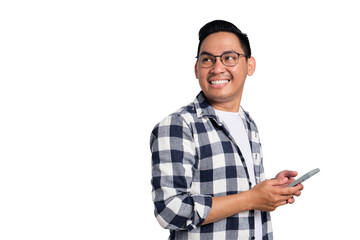 Smiling young Asian man in casual shirt holding smartphone and looking aside at copy space isolated...