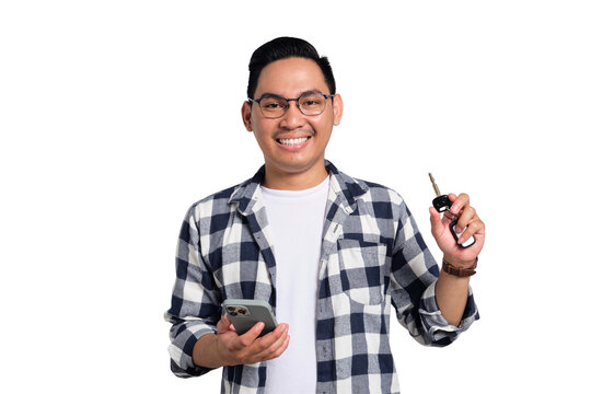 Smiling young Asian man in casual shirt holding smartphone and showing car key isolated on transparent background