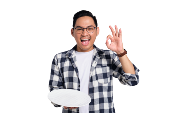 Happy young Asian man in casual shirt holding empty blank plate and making ok sign isolated on transparent background