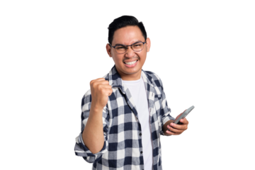 Excited young Asian man in casual shirt using smartphone for trading or chatting, making winning gesture isolated on transparent background