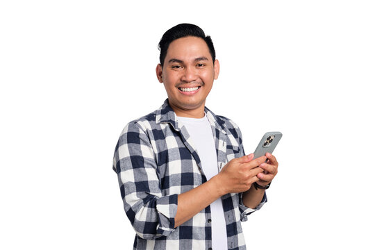 Smiling young Asian man in casual shirt using smartphone, chatting online, texting message, looking at camera isolated on transparent background - Powered by Adobe