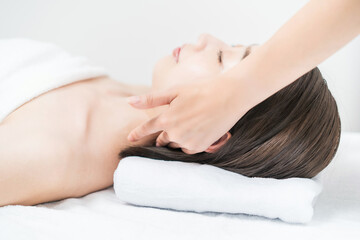 エステサロンで頭部をマッサージされる若い女性