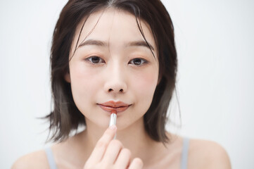口紅を唇に塗る若い女性