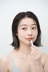 口紅を唇に塗る若い女性