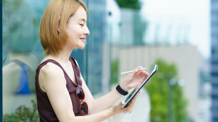 街なかで仕事をする女性（ノマドワーカーイメージ）