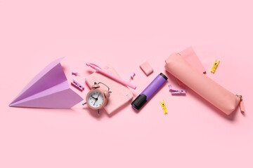 Composition with paper airplane, alarm clock and different school stationery on pink background