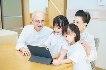 タブレットPCを操作するシニア夫婦と孫たち