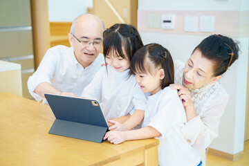 タブレットPCを操作するシニア夫婦と孫たち