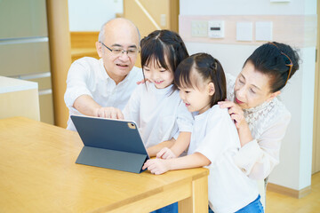 Fototapeta premium タブレットPCを操作するシニア夫婦と孫たち